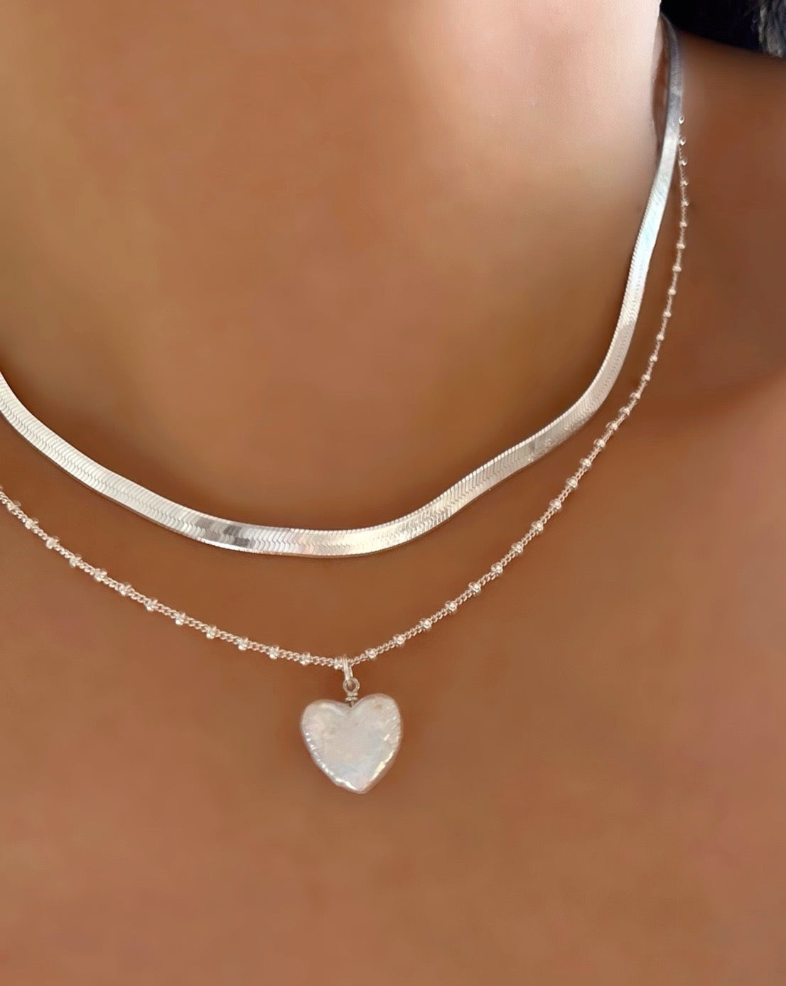 Silver Pearl Heart Pendant on a Sterling Silver Dot Chain Necklace layered with Silver Serpentine Necklace on a model 