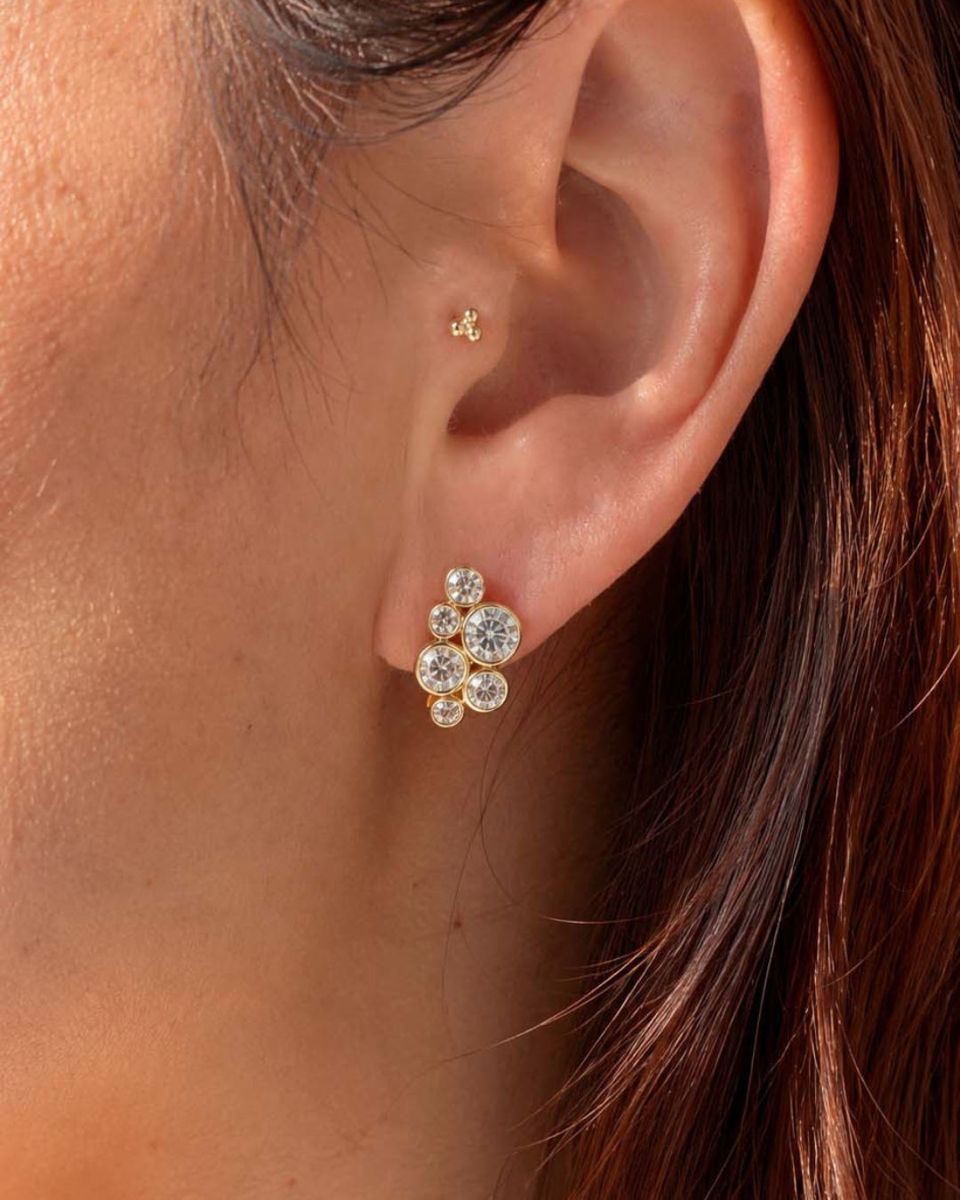 Woman wearing Romyli Bubble Cluster Huggies in 18k gold vermeil, styled in an ear stack