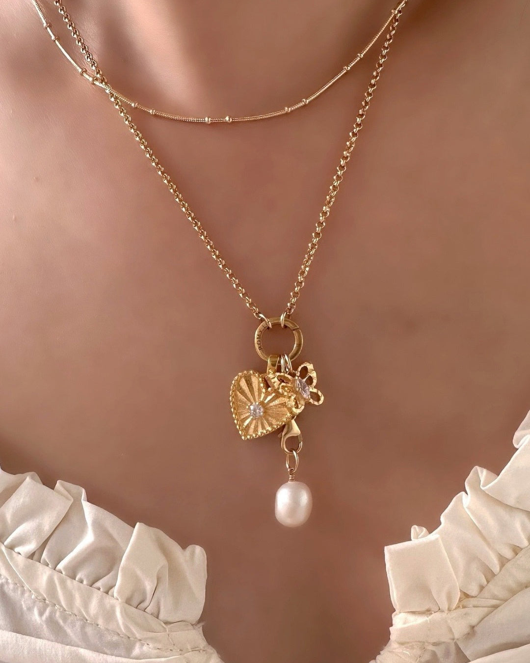 Model wearing Romyli Mix & Match Pendants with Petite Rolo Annex Link Necklace. Classic Pearl Pendant with Rolo Pendant Chain Connector, Heart Token Pendant and Textured Butterfly Pendant 