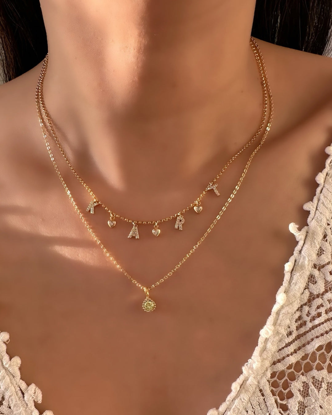 August Birthstone Necklace layered with Pave Initial Necklace on a model. 