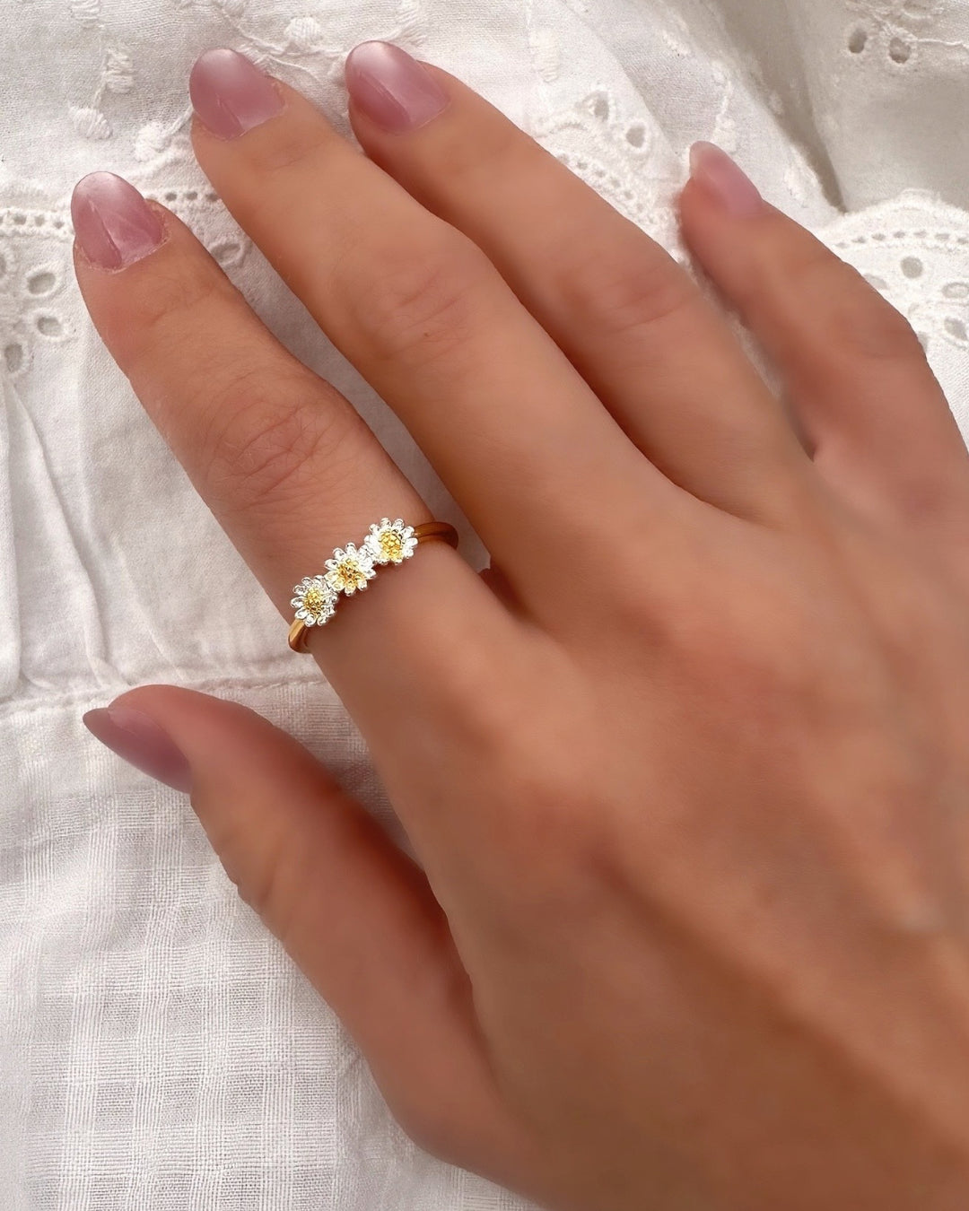 Model wearing Romyli’s Daisy Chain Ring, a dainty adjustable gold vermeil ring with three two-tone daisy motifs, perfect for everyday wear.