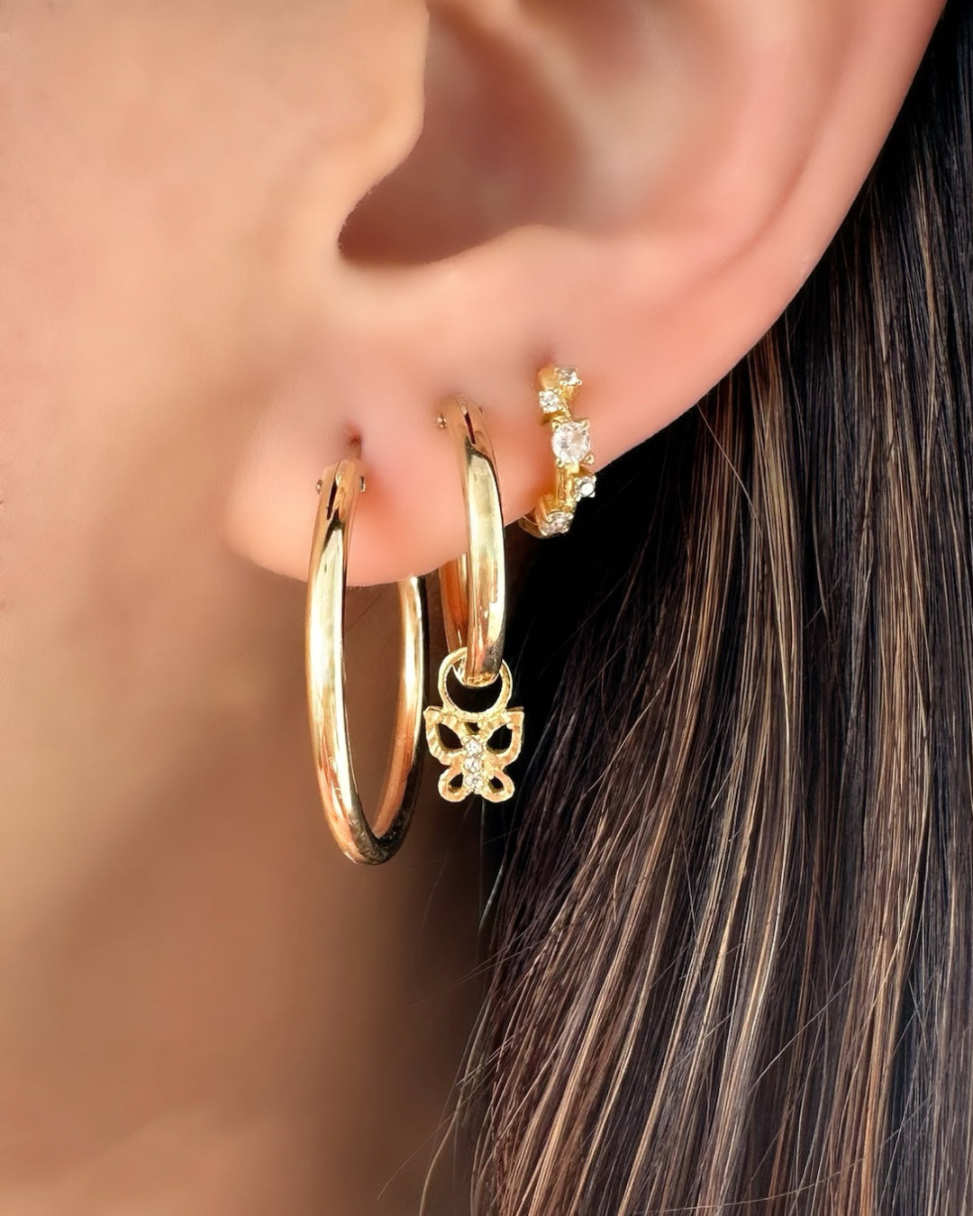 14k Gold Filled Large Euro Hoops on a model (27mm), stacked with Medium Euro Hoops and Butterfly Charm and Stellar Cluster Huggies. 