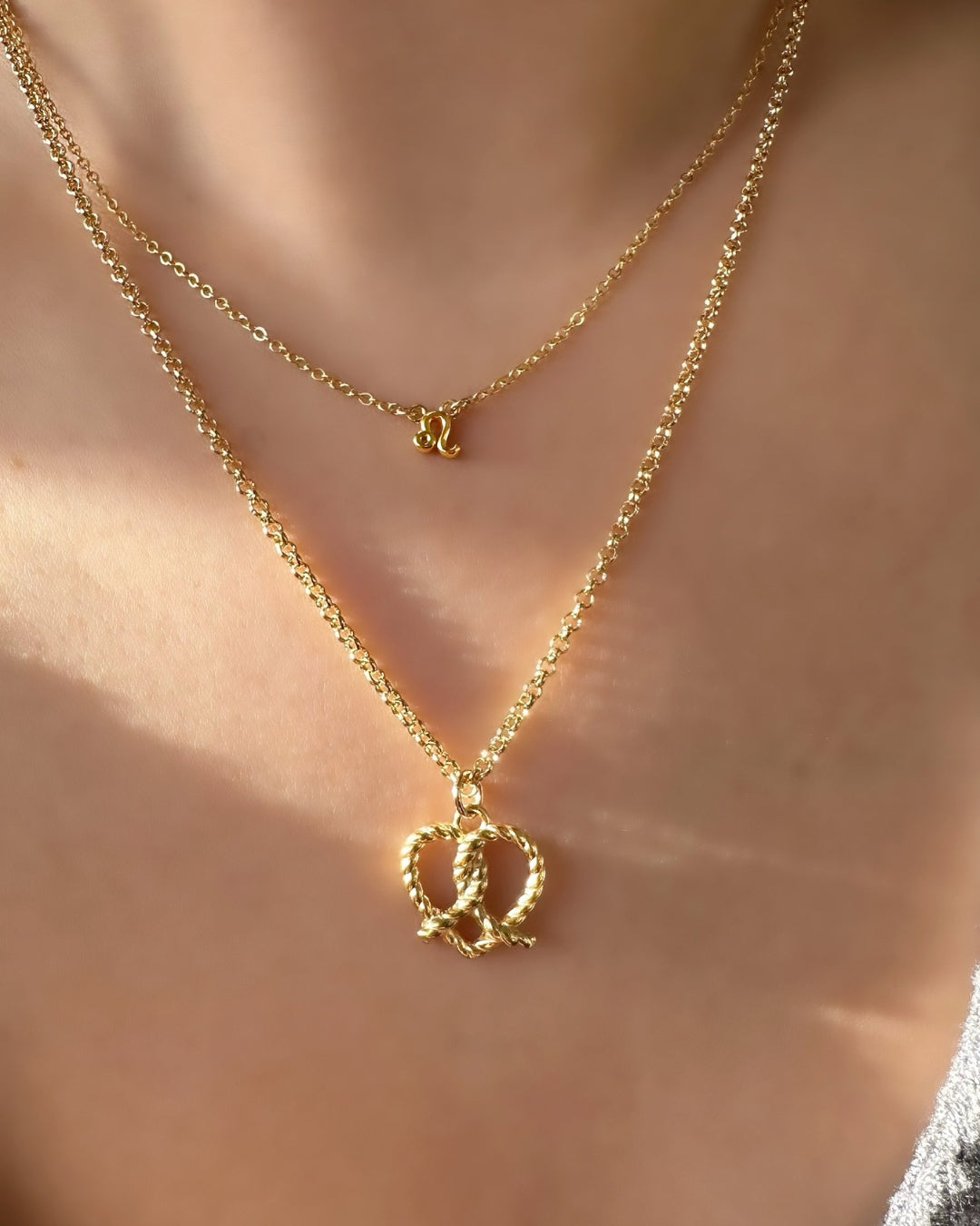 14k yellow gold fill pretzel heart pendant on a gold Rolo necklace chain on a model 