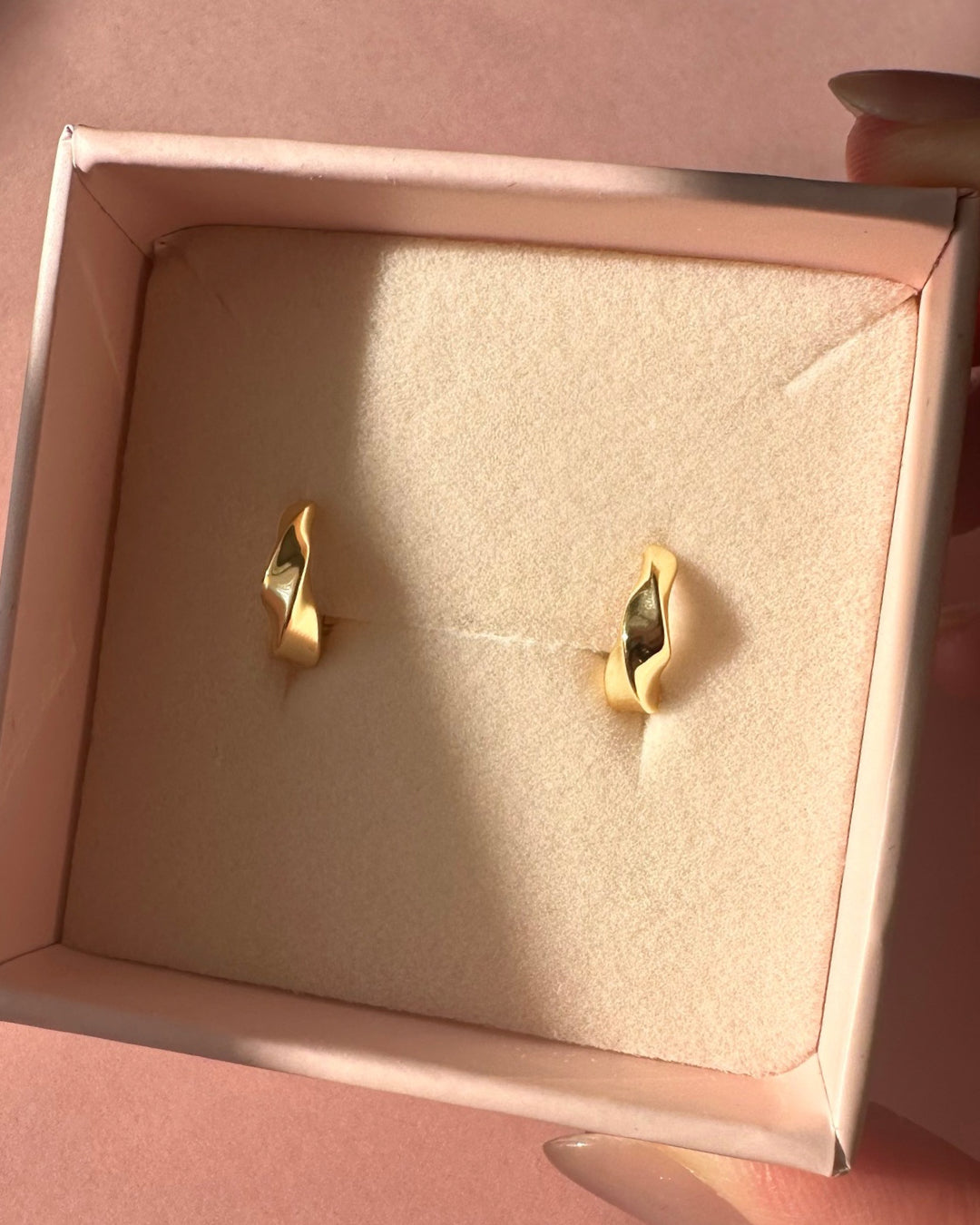 Gold molten dome Huggie hoop earrings in a pink Romyli jewelry box