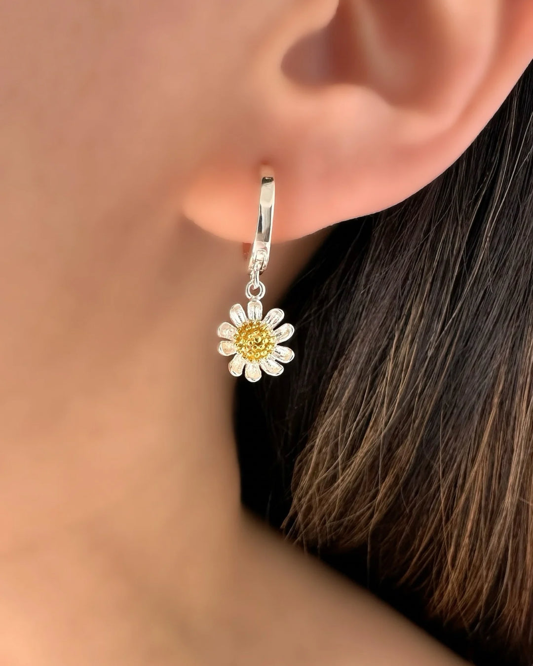 Model wearing Romyli’s Sterling Silver Daisy Bloom Hoops — small huggie earrings with silver and gold daisy charms, designed for everyday layering and spring styling.