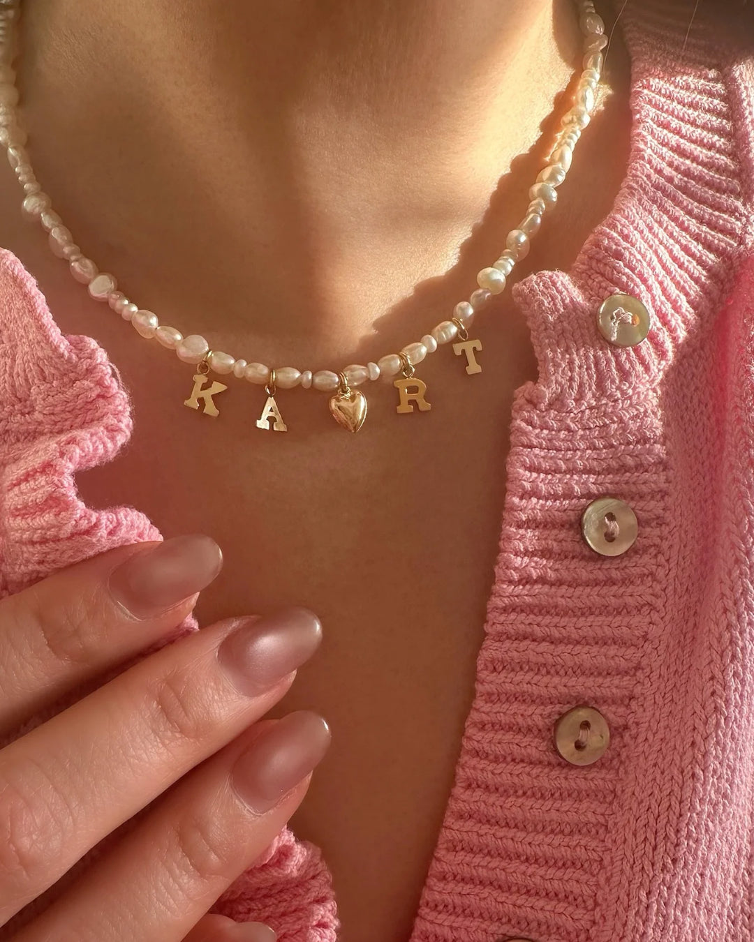 Model wearing gold-filled Classic Pearl Initial Choker with organic freshwater pearls and customisable initials and gold puffy heart charm. 