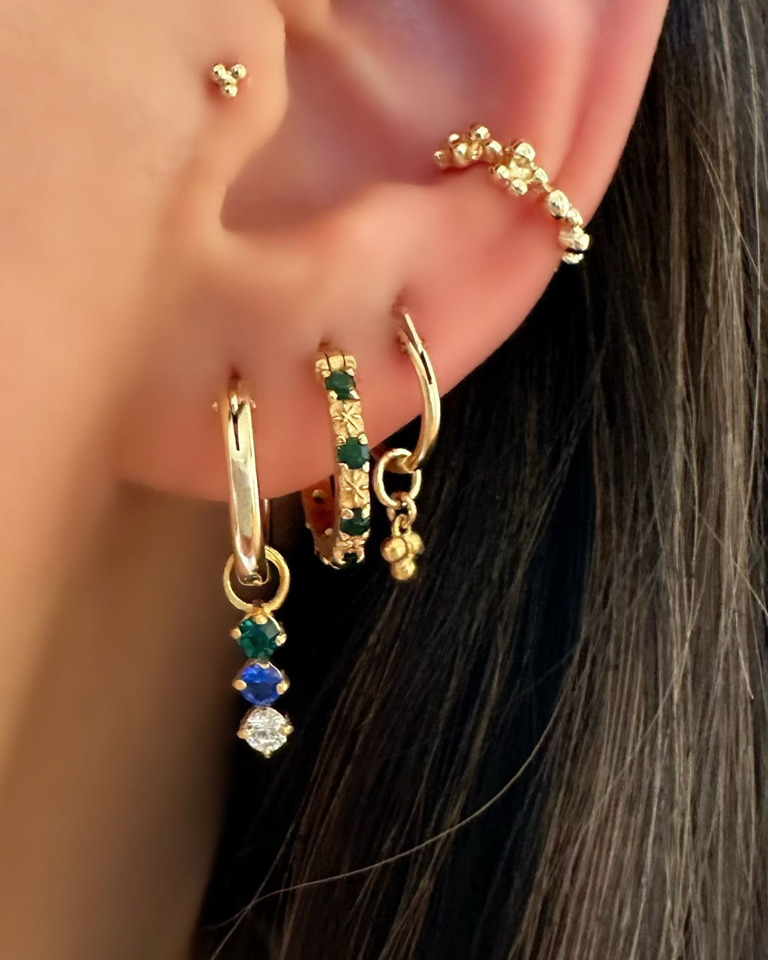 14k gold fill earring charm for hoops in emerald green, sapphire blue and white diamond cubic zirconia with gold hoop earrings on a model 