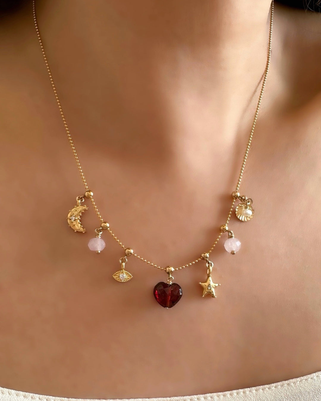 Garnet Heart Charm on a Charm Story Bead Necklace, stacked with meaningful gold and semi precious charms on a model. 