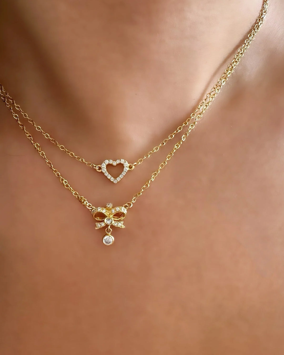 Gold Pavé Heart Necklace with cubic zirconia crystals on a delicate chain, made in Australia. Perfect Valentine’s Day gift, Galentine’s Day gift, or gift for besties. Necklace layered with the Vintage Bow Necklace on a model. 