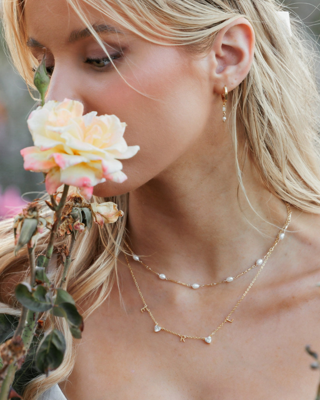 Model wearing freshwater pearl choker layered with gold necklace