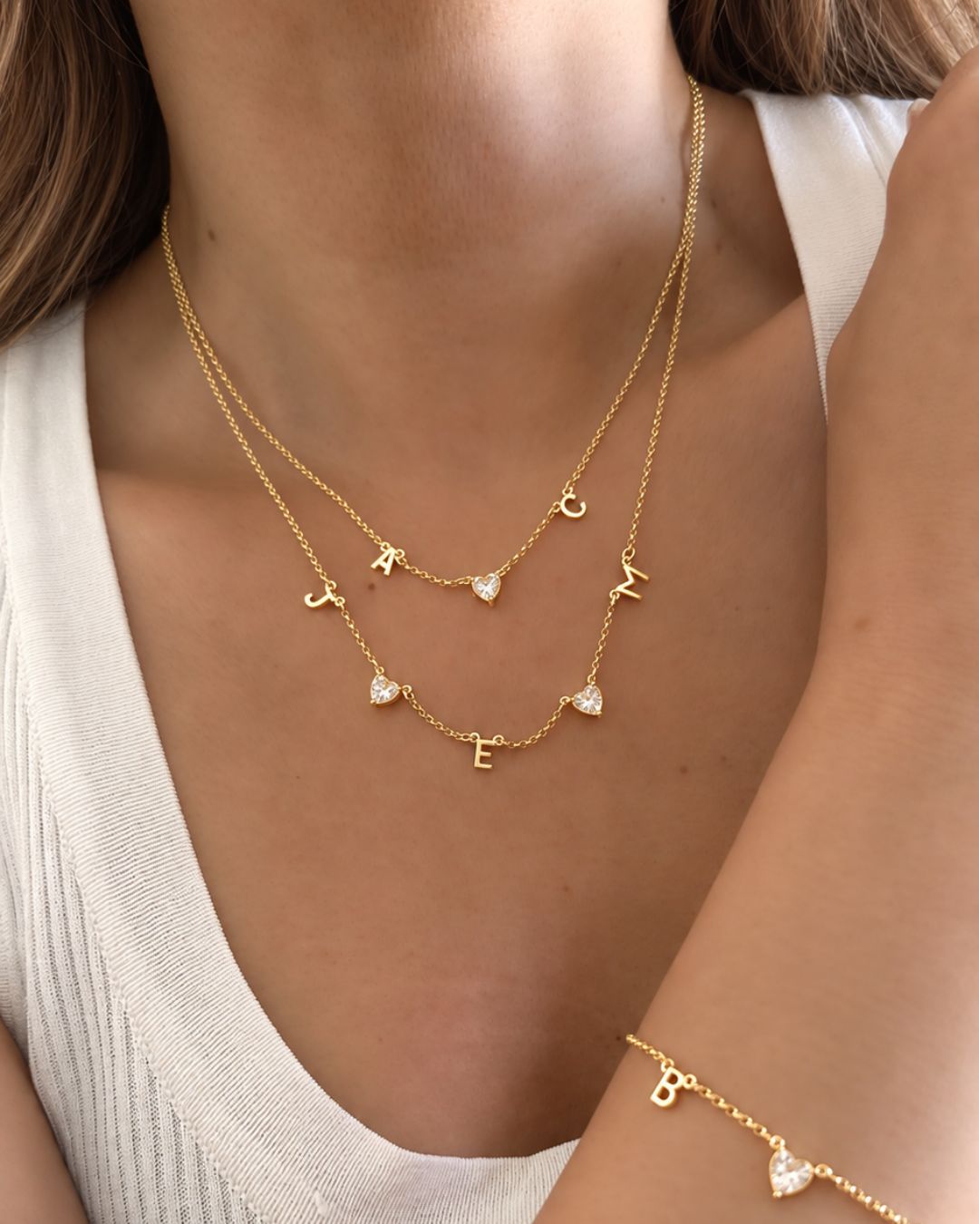 Model wearing the gold petite initial necklace with mini initial letters and heart gems in between. 