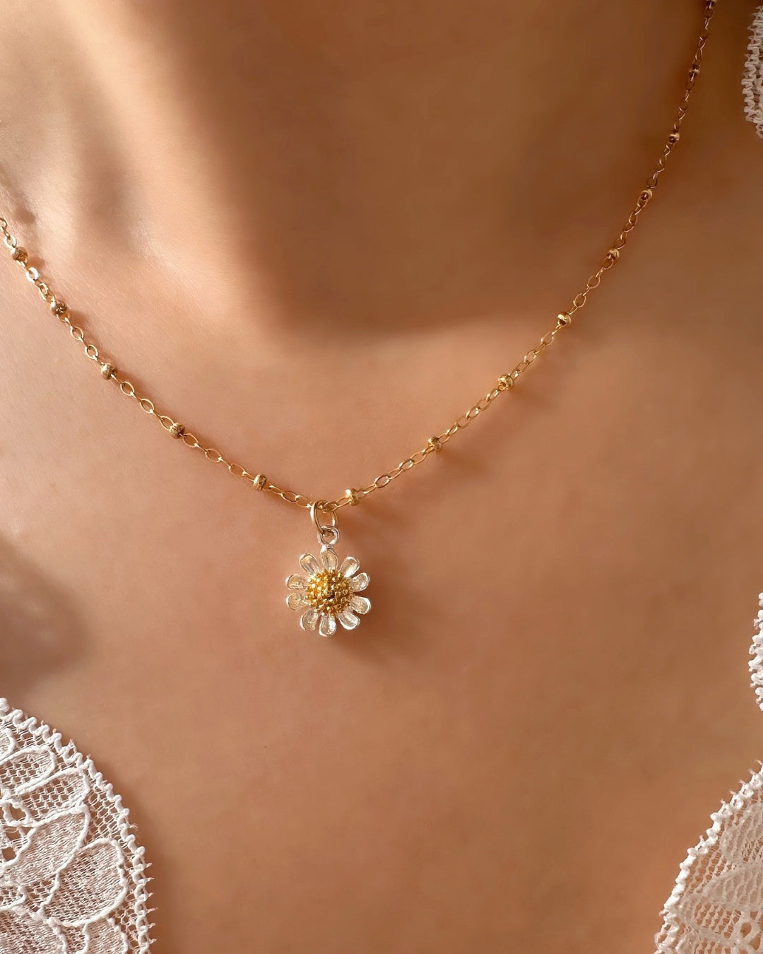 Model wearing the Gold Daisy Bloom Necklace by Romyli, a delicate gold-filled chain with a two-tone daisy pendant. Feminine dainty jewellery styled for everyday layering.