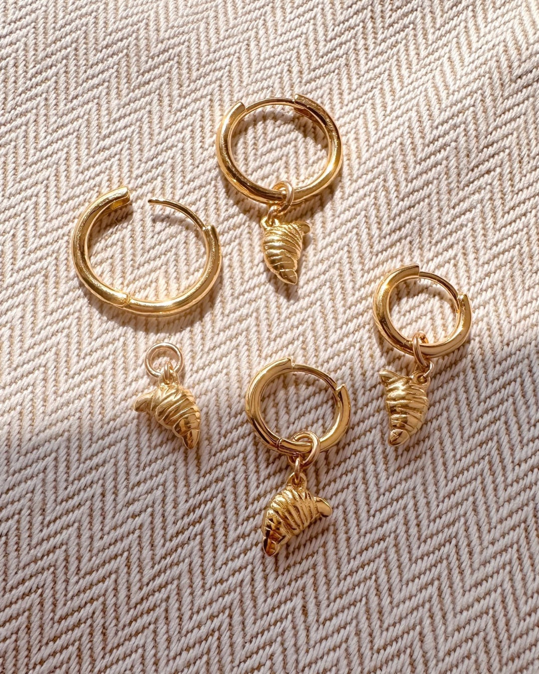 Flatlay of croissant charm hoops in medium and small. Earring charms are removable. 