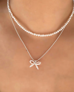 Freshwater Pearl Bow Pendant on a Sterling Silver Necklace Chain layered with a Pearl Choker on a model