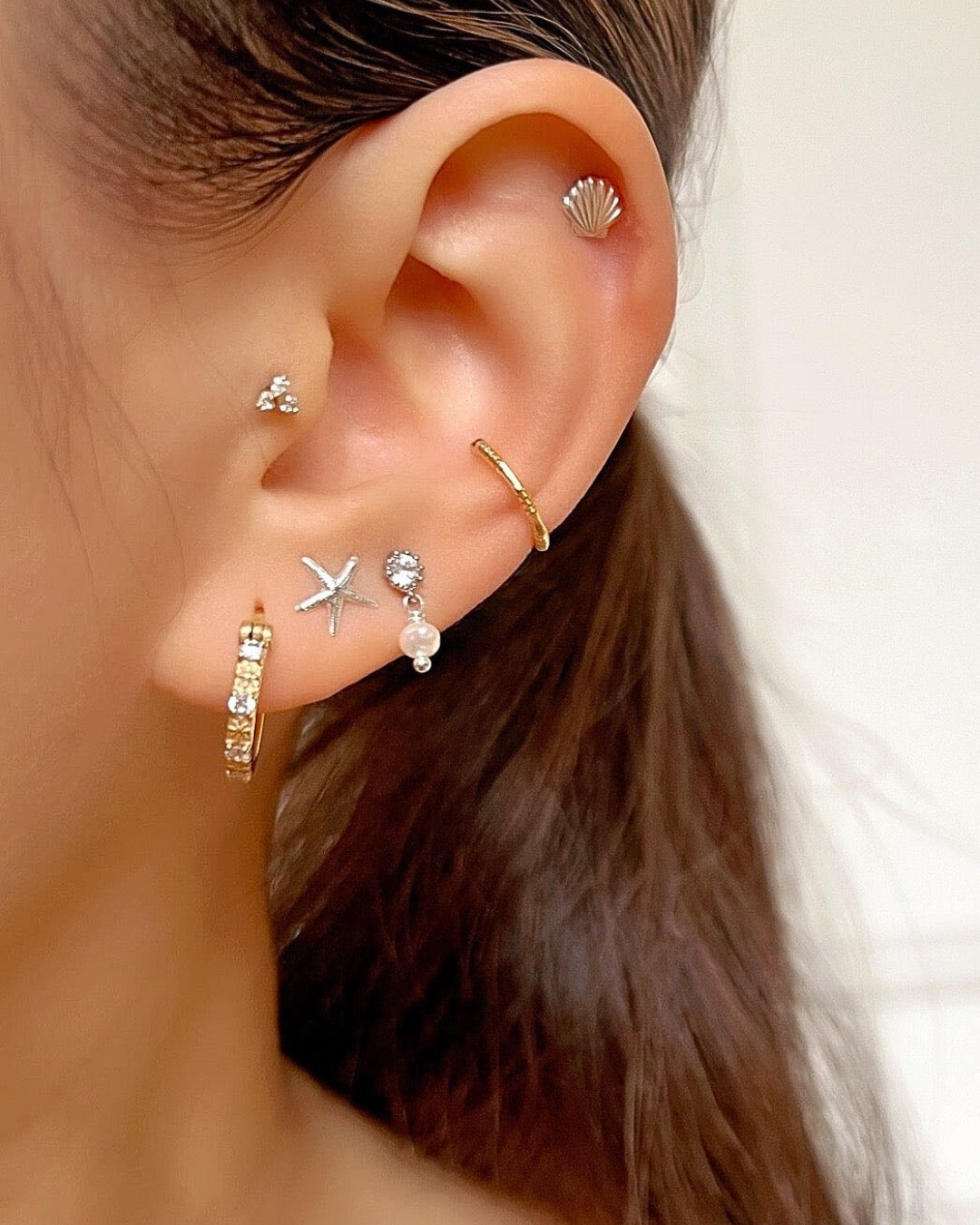 Sterling silver seashell stud post earrings with butterfly backs on a model