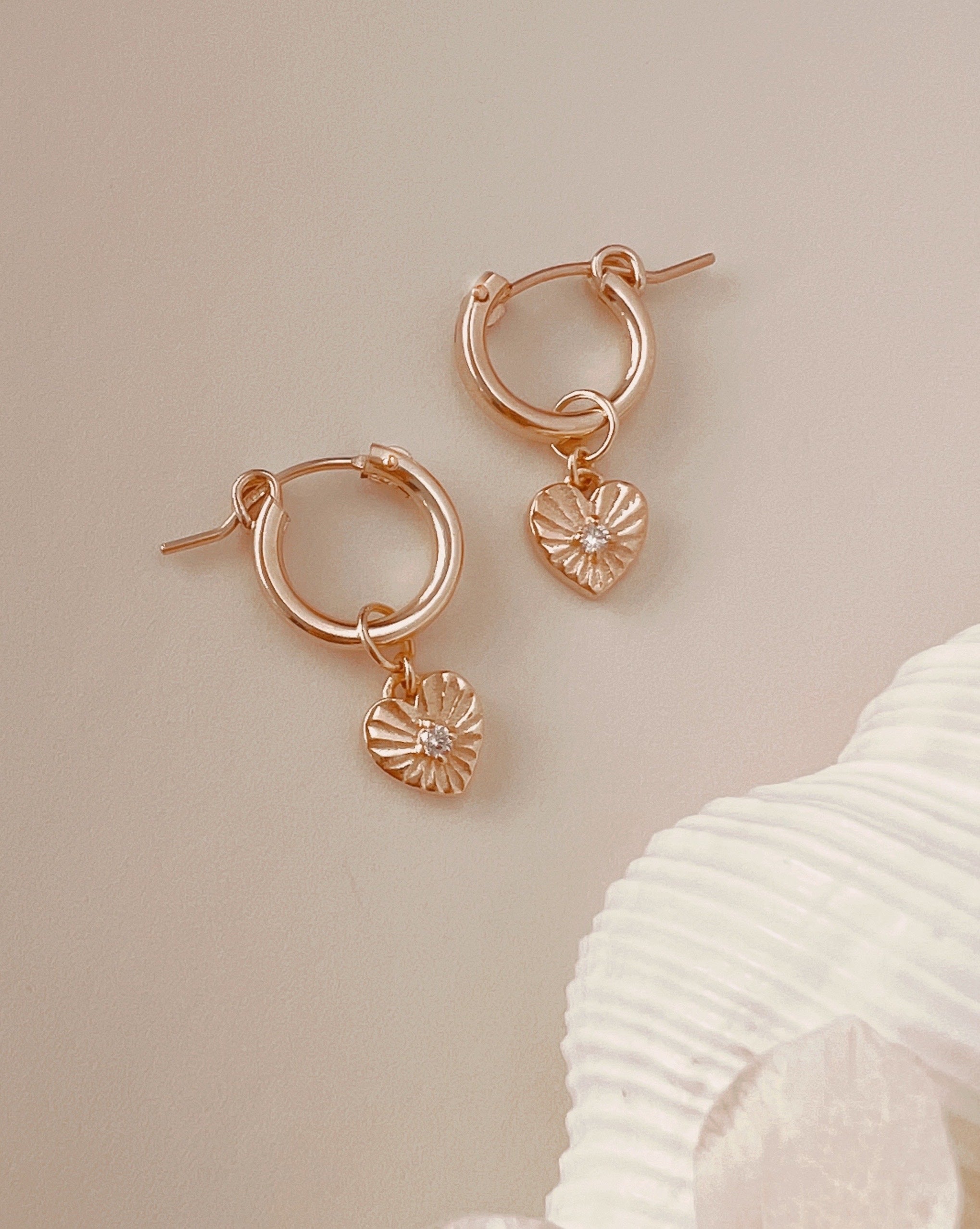 Love Amulet Charm Hoops with removable radiant heart charm, featuring a sparkling crystal center. Exclusive Romyli earring design for romantic, versatile style.