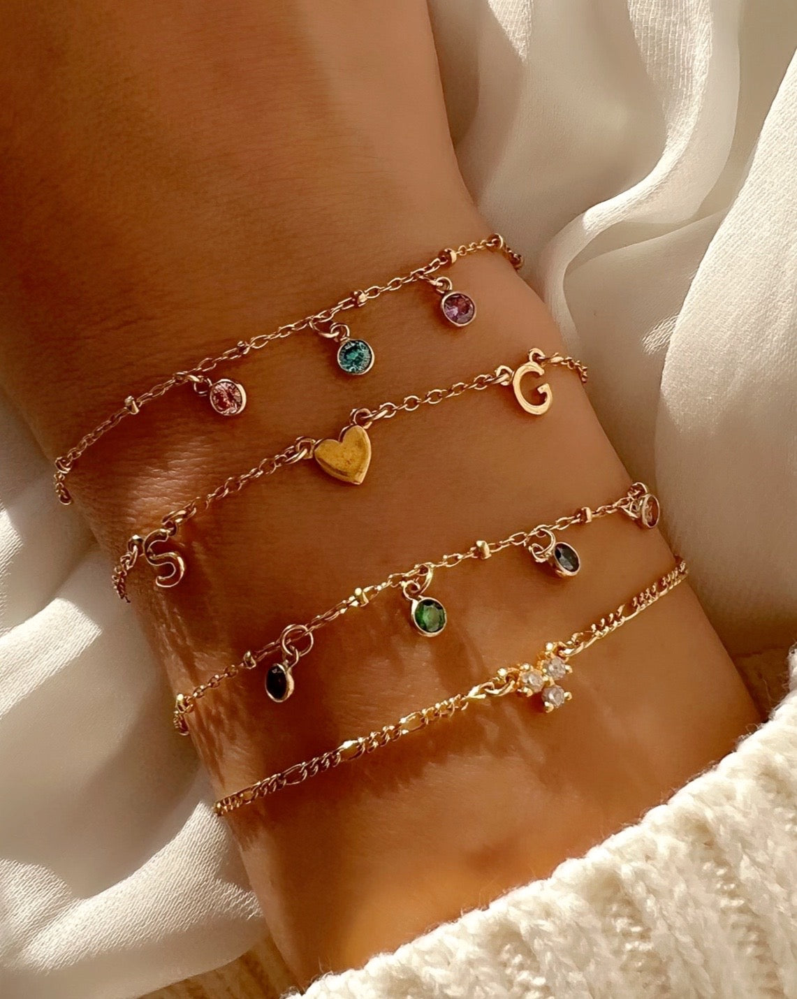 Gold Petite Birthstone Bracelet Colours and Months, including January Garnet, February Amethyst, March Aquamarine, April Diamond, May Emerald, June Alexandrite, July Ruby, August Peridot, September Sapphire, October Tourmaline, November Citrine and December Topaz Cubic Zirconia Crystals on a model 